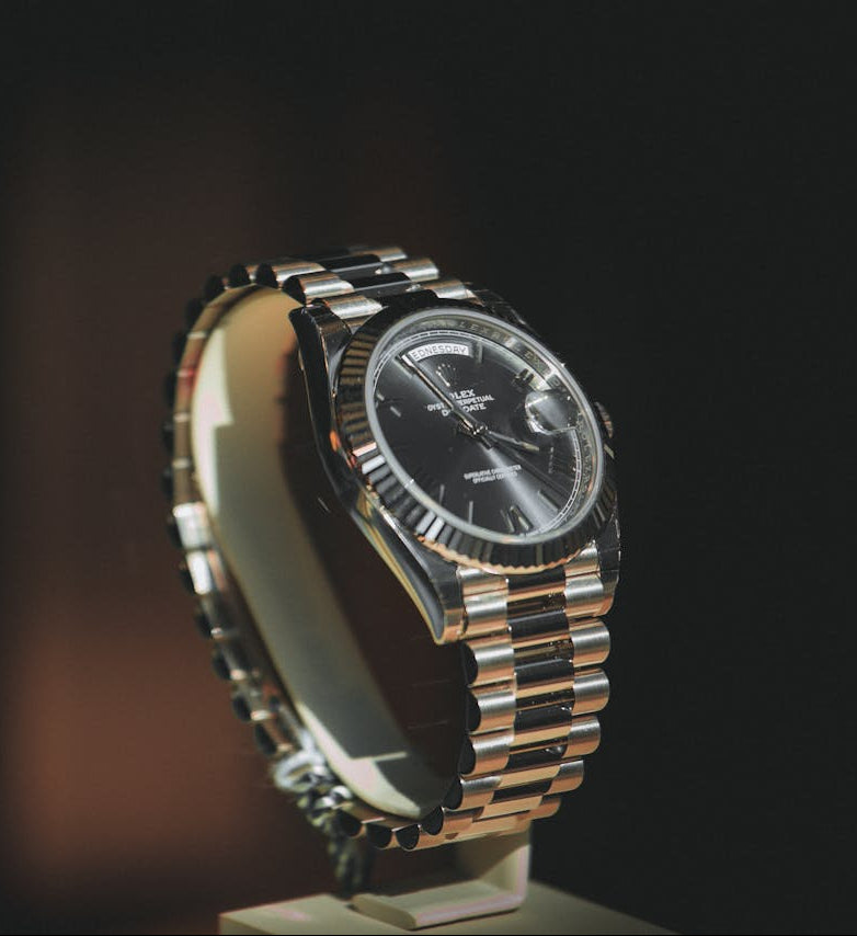Hands wearing a luxury gold timepiece with white dial and leather strap